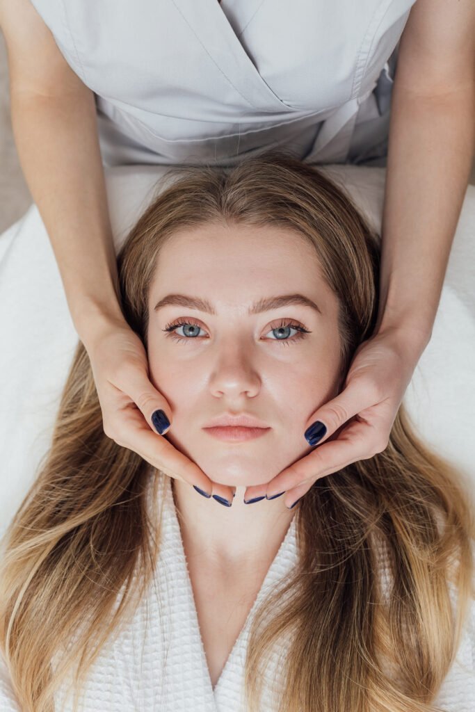 Young woman with long hair having her face gently held during a facial
