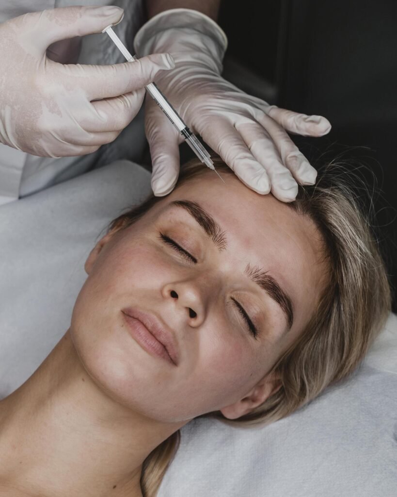 Woman with closed eyes receiving a cosmetic injection in the forehead area